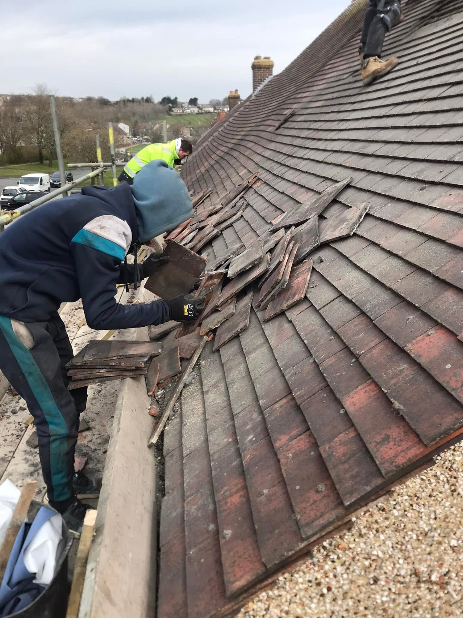 Workers handling tiles on a roof