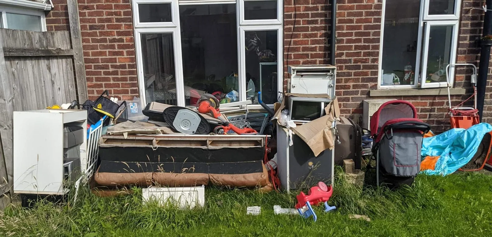 Sofa, appliance and household items grouped outside a home for clearance