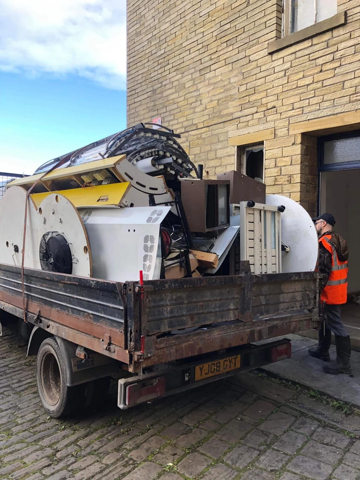 Truck loaded with cleared furniture and equipment beside a stone building