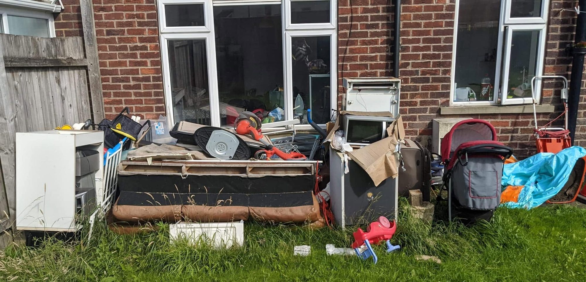 Sofa, appliance and household items grouped outside a home for clearance